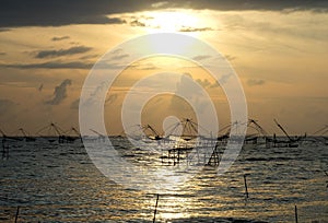 Silhouette of traditional fishing method using a bamboo square dip net with sunrise sky background