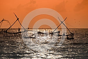 Silhouette of traditional fishing method using a bamboo square dip net with sunrise sky background