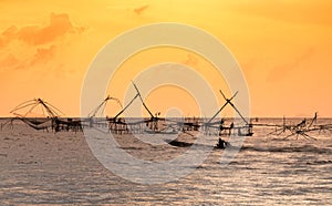 Silhouette of traditional fishing method using a bamboo square dip net with sunrise sky background