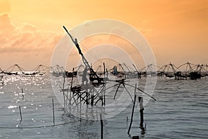 Silhouette of traditional fishing method using a bamboo square dip net with sunrise sky background