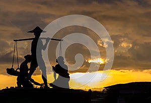 Silhouette of Traditional Thai Farmer Carry The Baskets of Rice in His Hand with Women on The Floor at The Corner. Labor Day