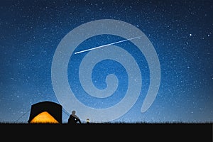 Silhouette of traveler camping on the mountain and night sky with stars. Space background.