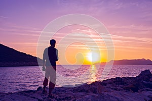 Silhouette of traveler who stands on the rock seashore