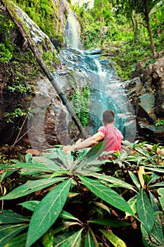 Silhouette traveller man explore waterfall hidden in tropical rainforest jungle