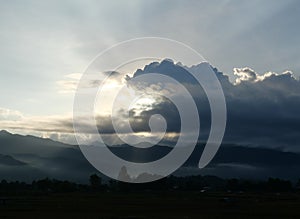 Silhouette of tree and mountain with sunbeam