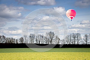 Silhouette of trees with clouds in the sky and a red hot air balloon