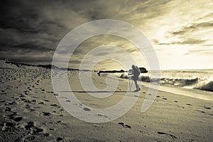 Silhouette of trekker traveler walking on sandy beach with waves hot sunny day in october on atlantic coast