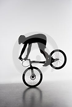 silhouette of trial biker performing front wheel stand