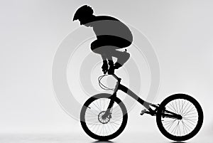 silhouette of trial biker standing on handlebars with hands