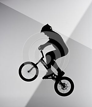 silhouette of trial cyclist jumping on bicycle on abstract grey