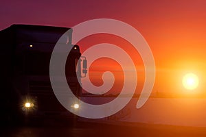 Silhouette Truck with container on highway, cargo transportation concept. Sunset background with copy space