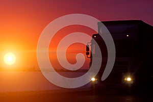 Silhouette Truck with container on highway, cargo transportation concept. Sunset background with copy space