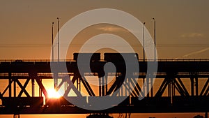 Silhouette of a truck driving over the bridge at sunset