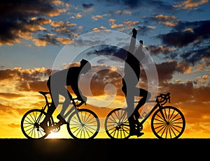 Silhouette of two cyclists riding a road bike