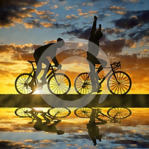 Silhouette of two cyclists riding a road bike