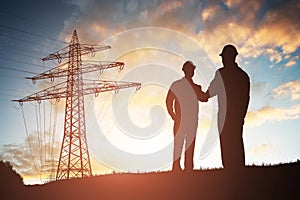 Two Engineers Shaking Hands Against Dramatic Sky