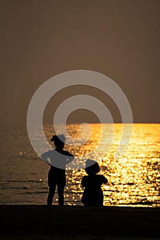 Silhouette of two girls looking to the sea with sunset