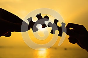 Silhouette of two hands connect jigsaw together