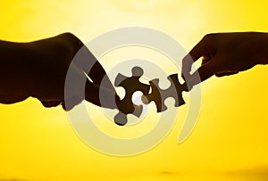 Silhouette of two hands connect puzzle together