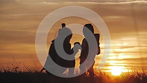 Silhouette of two happy children playing on meadow, sunset, summertime.