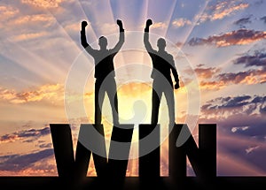 Silhouette of two happy men with raised arms standing on the word win.