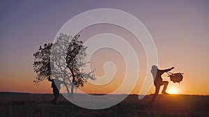 Silhouette of two hikers tourist running jumping funny and throwing backpacks at sunset. Slow motion. Concept travel and