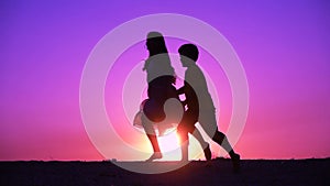 Silhouette of two kids runniing at sunset
