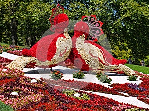 Silhouette of two large birds made of red and white flowers against the background of a beautiful flowerbed and