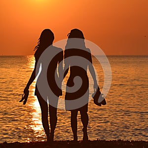 Silhouette of two lesbian girls on the beach in sunset
