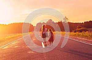 Silhouette two little girls walking on the road . Sisters enjoyed a Holiday over blurred summer nature. Concept People and nature. photo