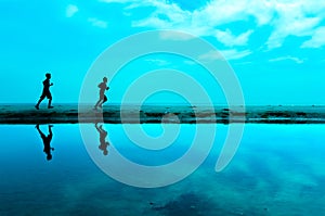 Silhouette of two man running at the beach