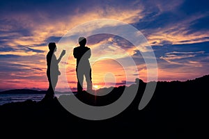 Silhouette two man standing on the clift during sunset