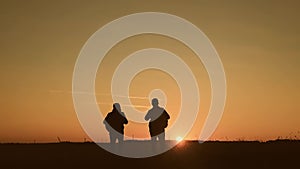 The silhouette of two man standing on the top of mountain with backpacks and use phone for navigation. Lifestyle, travel