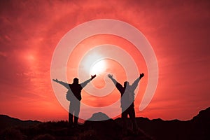 The Silhouette of two man with success gesture