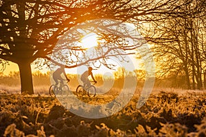 Silhouette of two men riding bicycles.