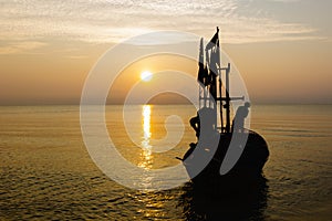 Silhouette of two people on a fishing boat that is about to go fishing in the morning sun.copy space