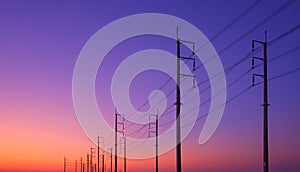 Silhouette two rows of electric poles with cable lines against colorful twilight sky background after sundown