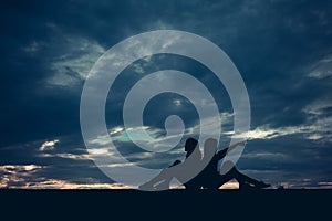 Silhouette of two women sitting lean