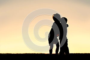 Silhouette of Two Young Children Hugging at Sunset