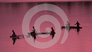 SILHOUETTE Unrecognizable local fishermen fishing in small boats at pink sunrise