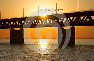 Silhouette of the Utsiktspunkt Ã–resundsbron bridge over the water with orange sky in background