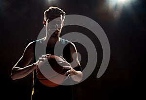 Silhouette view of a basketball player holding basket ball on black background