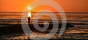 Silhouette view of a man standing on the North Sea Coast at sunset in Cuxhaven town, Germany