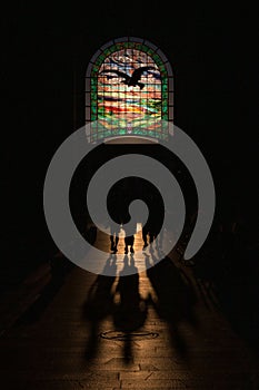 Silhouette view of small group of people walking on the church aisle against stained glass window