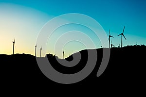 Silhouette view of a wind turbines on top of mountains, sunset sky, in Portugal