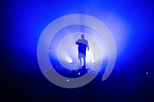 silhouette of a vocalist and microphone stand on stage in a blue haze.