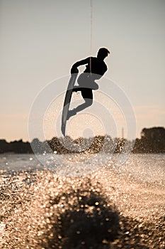 silhouette of wakeboarder jumping high making tricks in the air