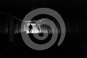 Silhouette of a walking man at the end of the tunnel, in the hands of men bags and packages, background road pedestrian