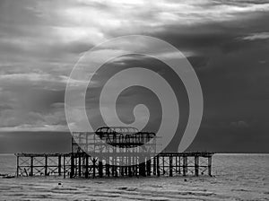 a silhouette of the West Pier, Brighton, under a dark, gloomy sky