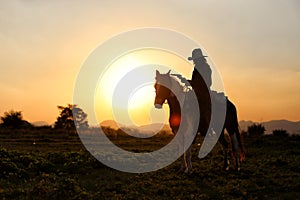 Silhouette of western riders against amber colored sunset